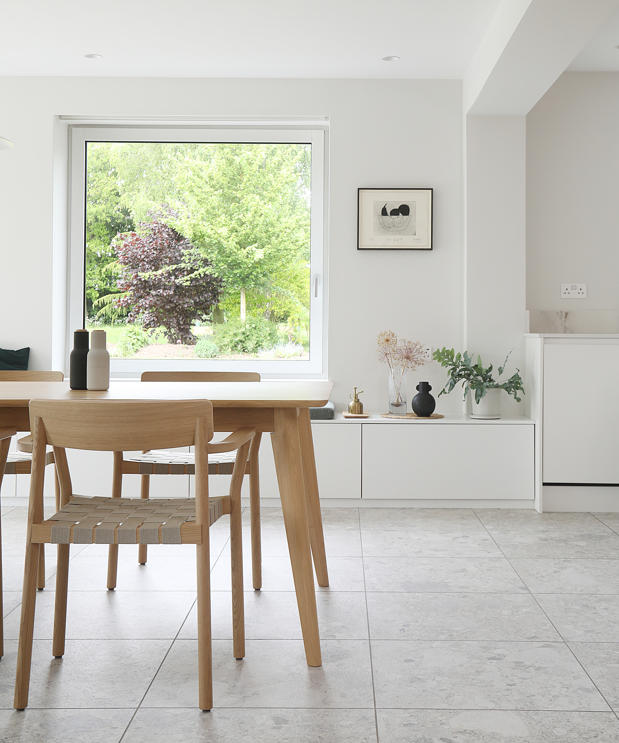 Light floor tiles used in the dining area of a home with white walls and pale wood dining table