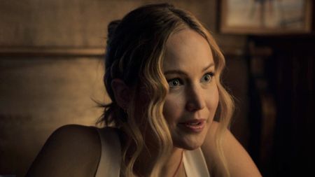 Jennifer Lawrence, wearing a white tank top and hair pulled back, sitting at dinner in 2023's comedy No Hard Feelings.