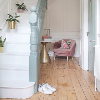 Hallway with wooden plank flooring, gold table and pink armchair
