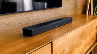 Bose Soundbar 600 on a wooden table beneath a TV