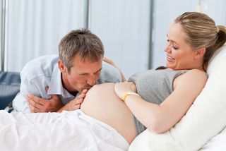 man kisses his wife's pregnant belly