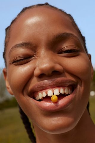 woman with orange supplement pill between teeth