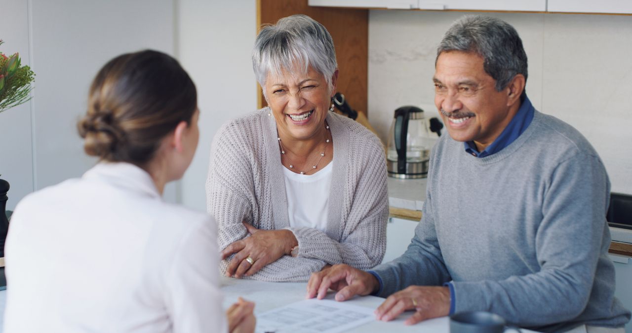 A couple meets with a financial adviser at a small table.