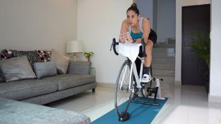 A woman training on a stationary bike inside her home.