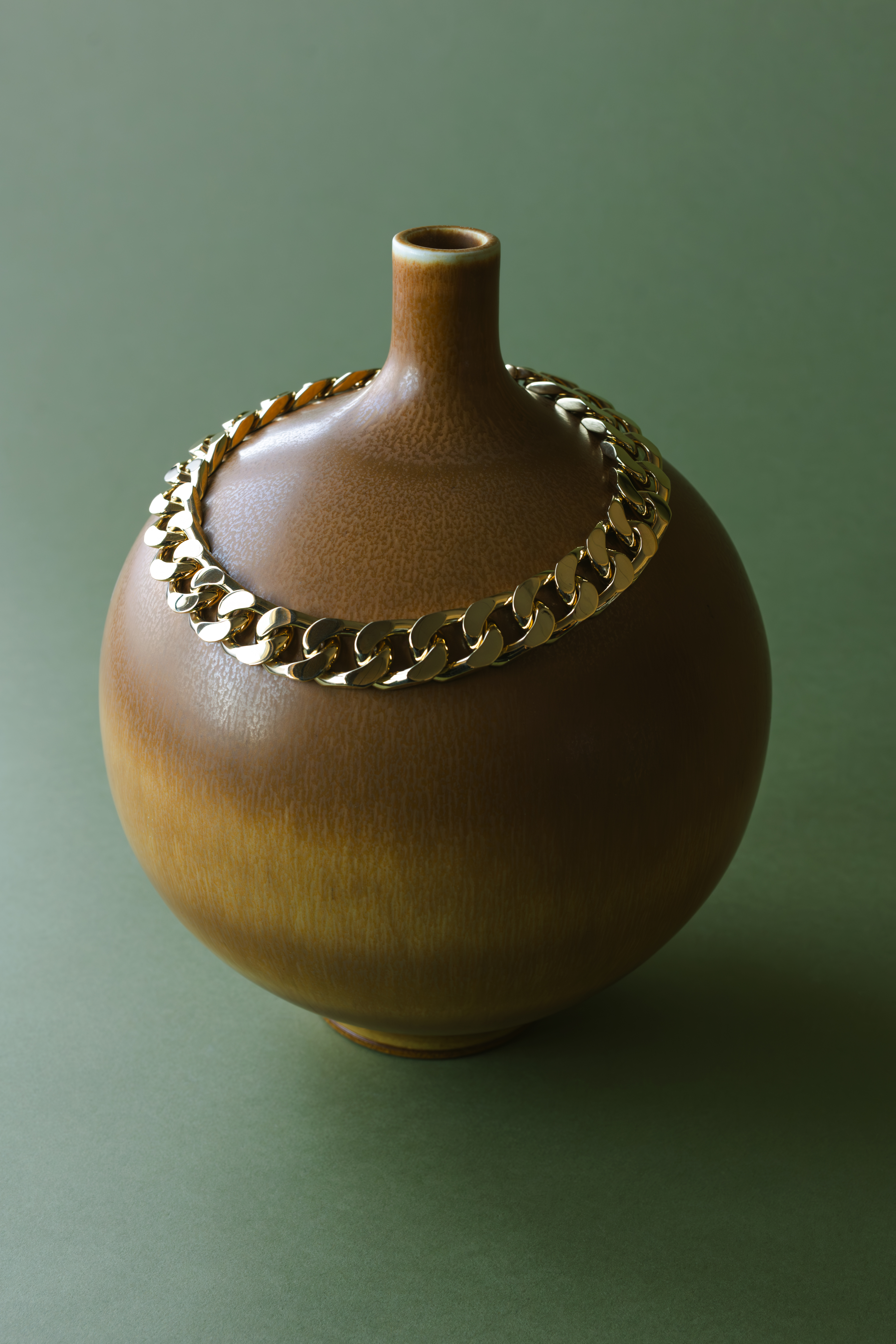 ceramics and jewellery against green and brown backgrounds