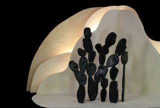 A screen by Virginia Gordon formed of stacked black pebble shapes and a white organic formed background