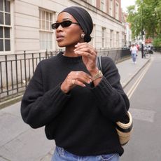 Marilyn Nwawulor-Kazemaks in a headband, black sweater, and woven handbag.