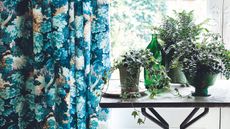 Blue and green curtains next to a table with potted plants on top.
