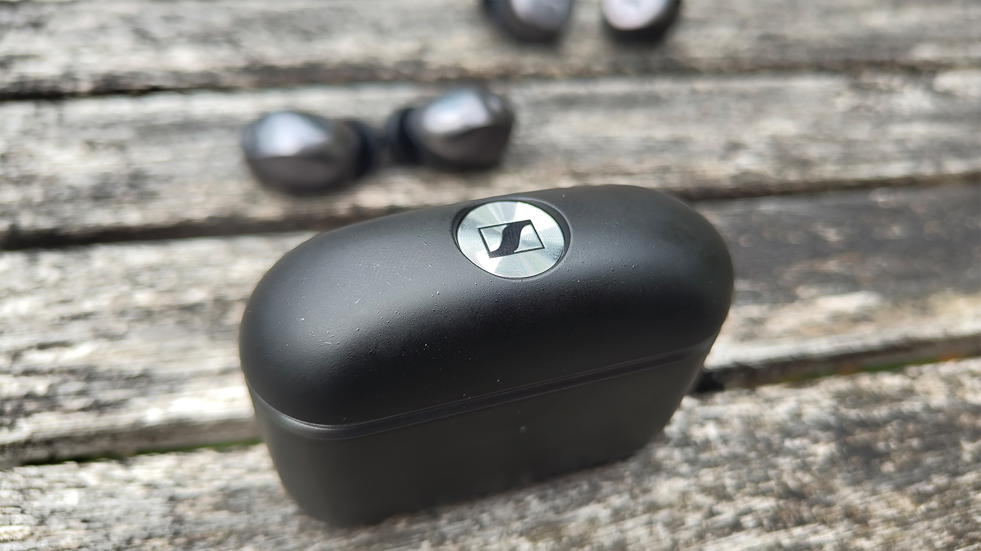 Sennheiser Momentum True Wireless 5 wireless earbuds outside case on wooden outdoor table