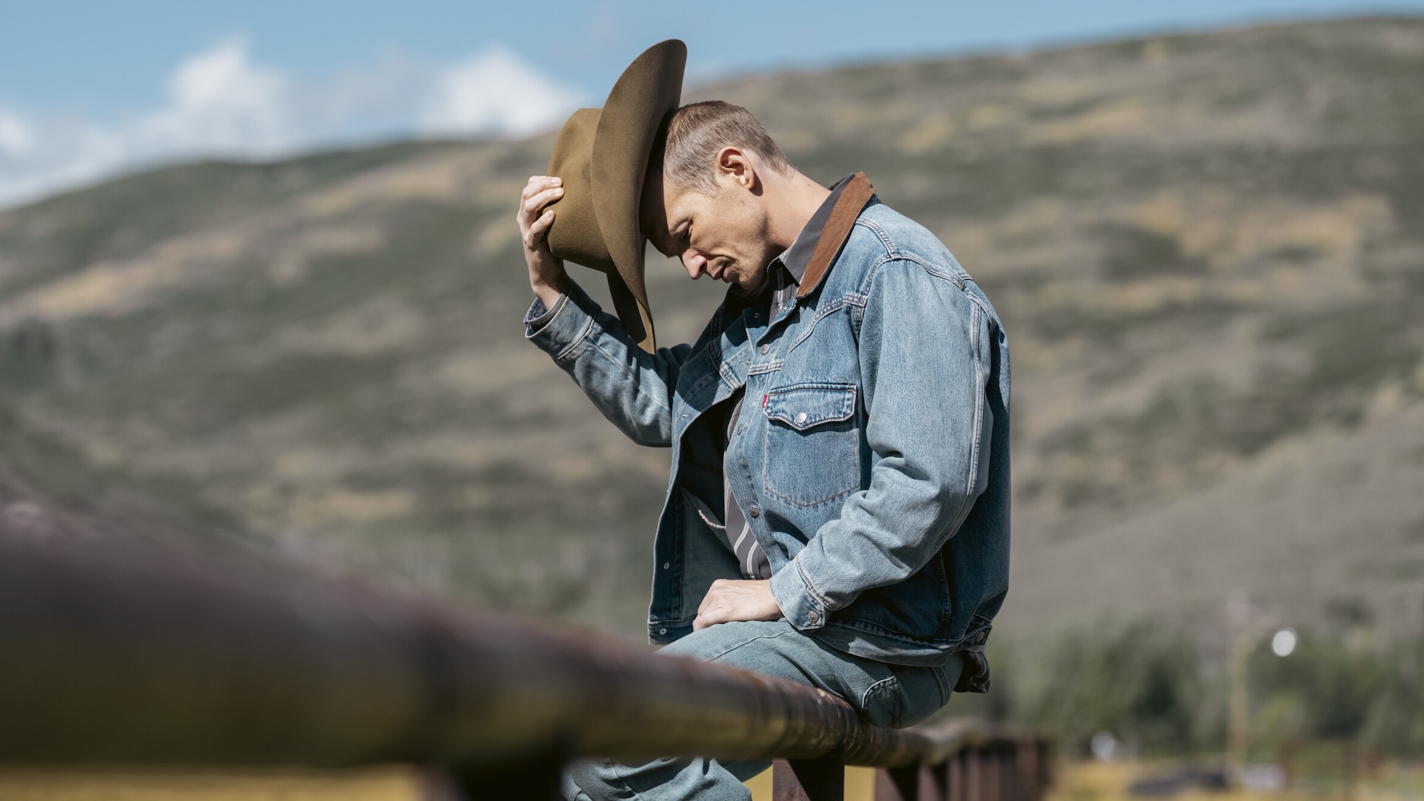 Jimmy sitting on iron fence and tipping his hat forward in Marshals Season 2 premiere