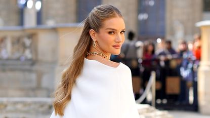 Rosie Huntington-Whiteley wearing white looks over her shoulder with glowy skin thanks to the best iS Clinical products