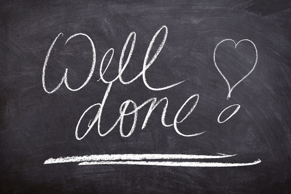 The words &quot;Well Done&quot; are handwritten in chalk on a blackboard. There is a heart next to them, also written in chalk.