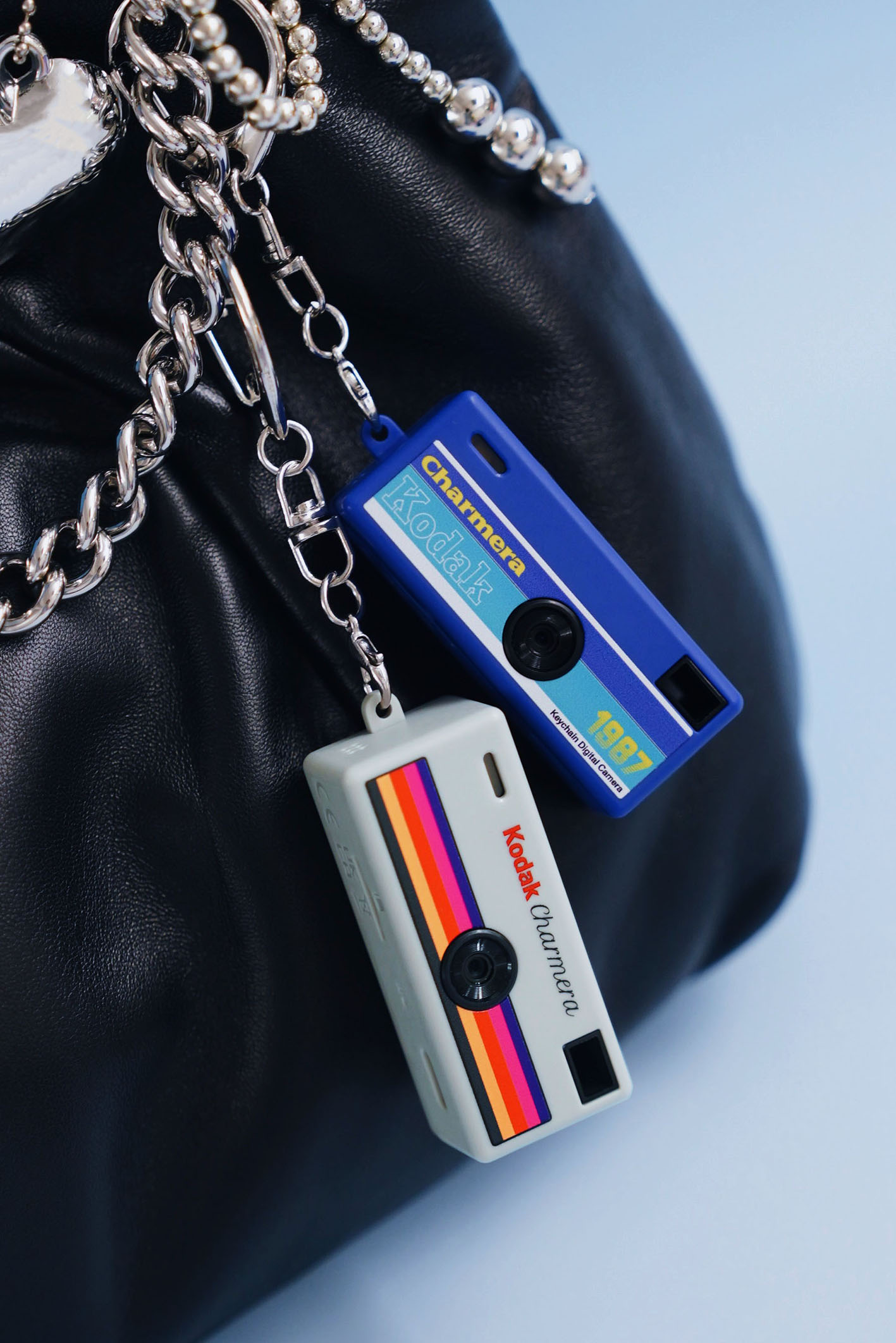 Two Charmeras added to a keychain that is attached to a black bag
