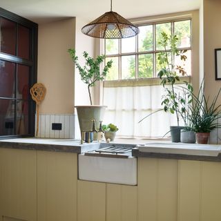A yellow kitchen with a cafe curtain on the window