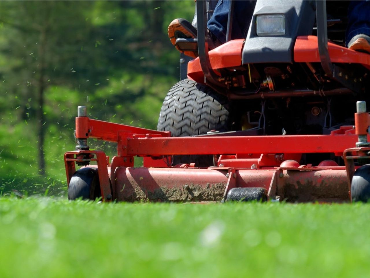 A red riding lawn mower cutting grass