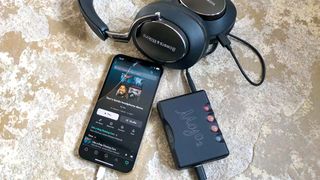 Chord MoJo 2 DAC with iPhones and Bowers & Wilkins Px8 headphones on a stone floor