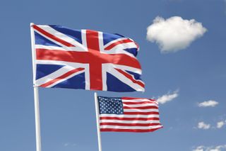 The national flags of the United Kingdom and United States pictured side by side against a blue sky backdrop