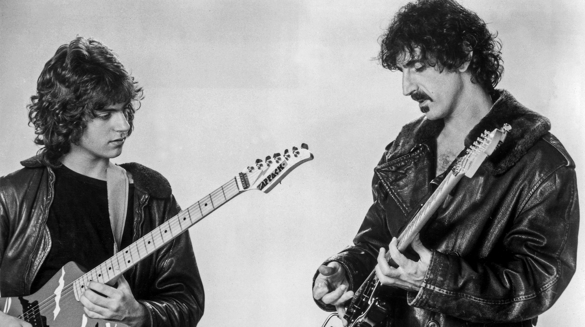 circa 1985: Promotional studio image of American rock guitarist and composer Frank Zappa (1940 - 1993) playing the electric guitar with his son Dweezil Zappa, early.