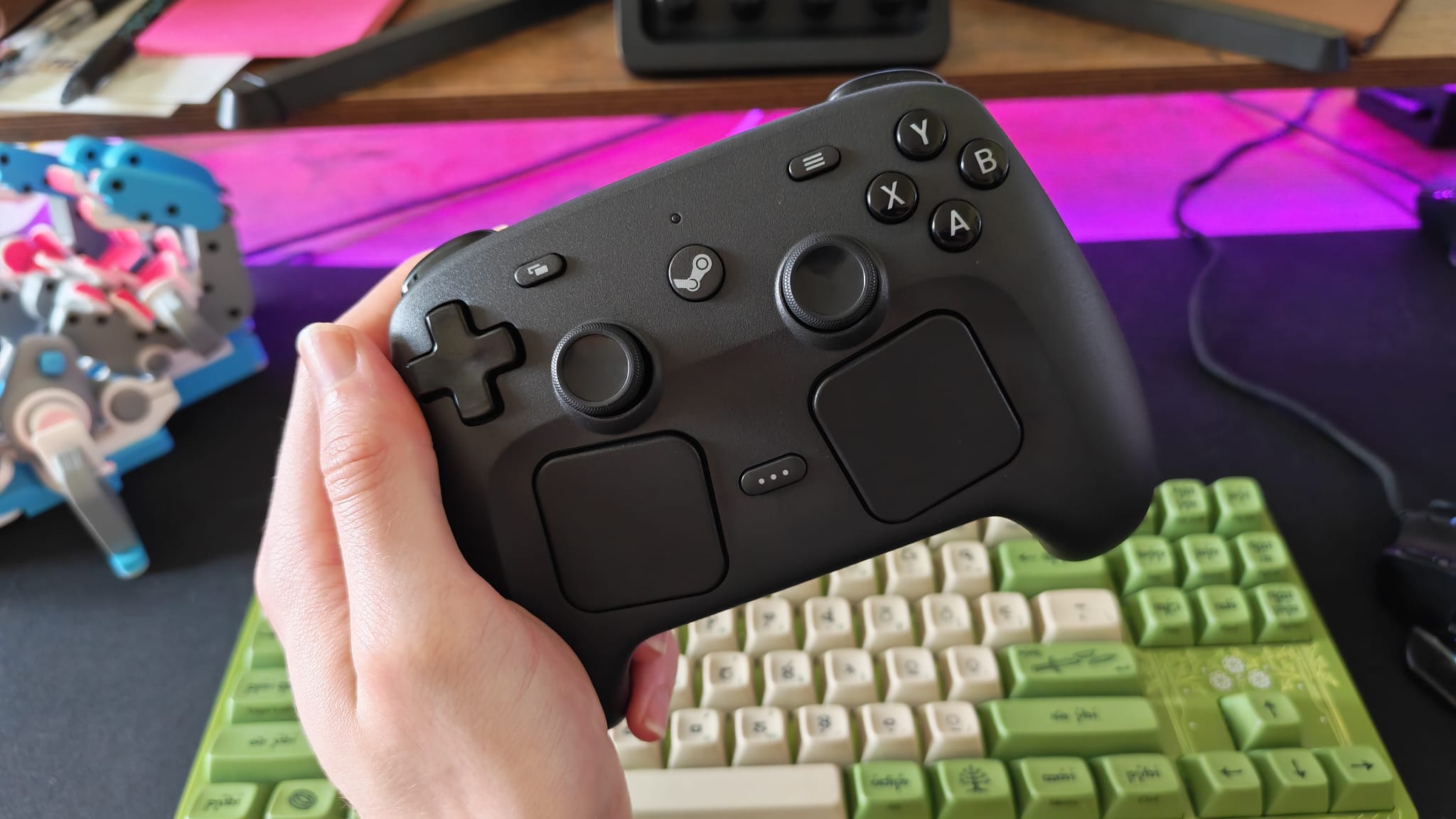 A reviewer holding a Steam Controller over a gaming desk