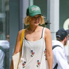 Gigi Hadid wearing a white floral dress with checkered Vans slip-ons in New York City July 2024