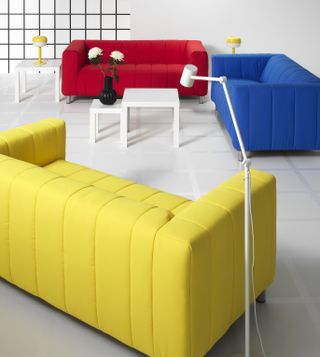 IKEA box-y shaped sofas in red, blue and yellow in a white room