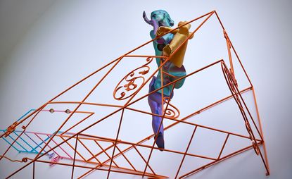 Orange steel frame with a sculpture of a woman