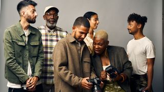 Group of people standing around two photographers looking at recently taken photos