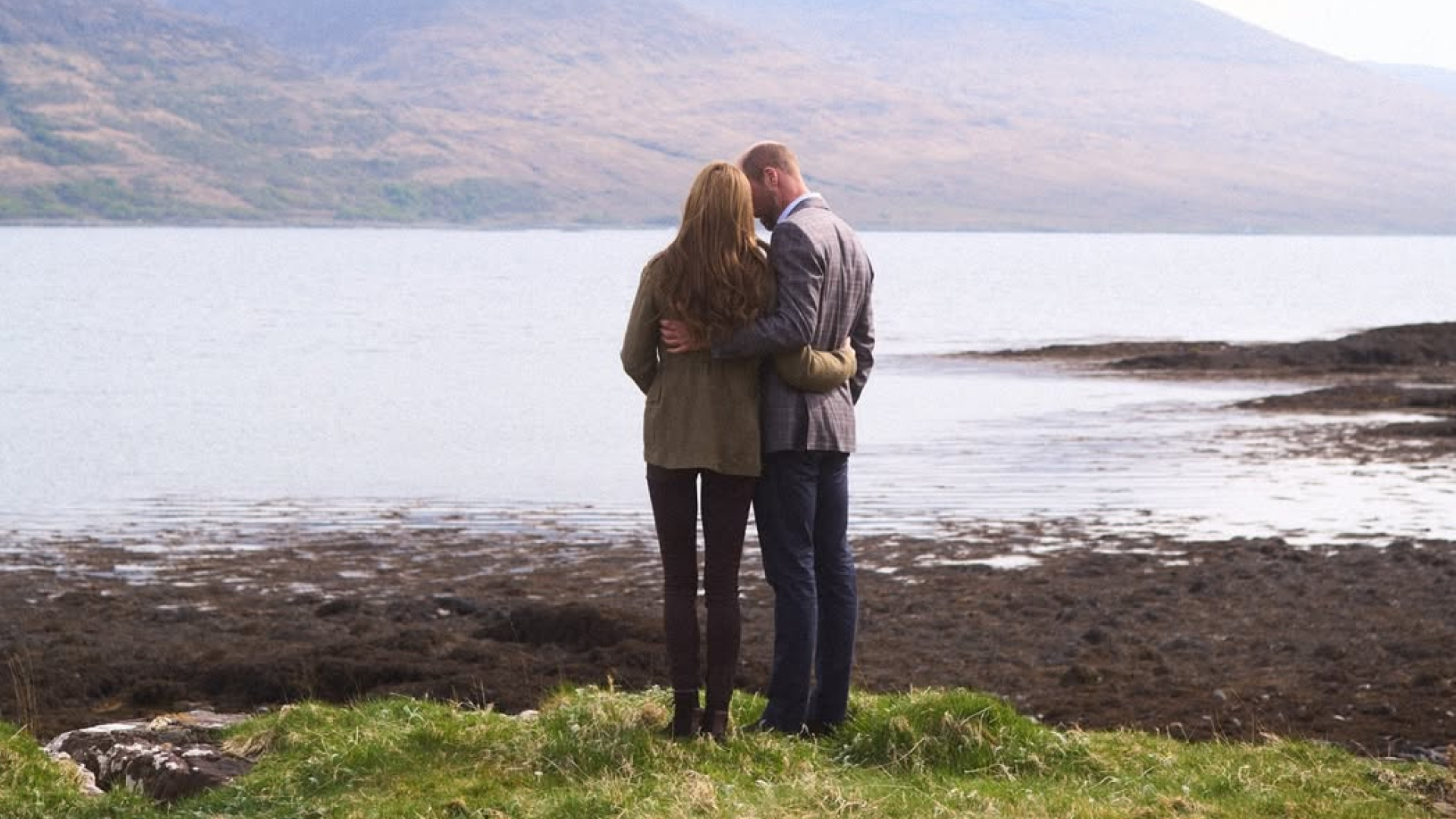 Kate Middleton and Prince William standing with their backs to the camera looking at a lake and mountains in Scotland