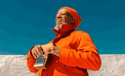 new age musician laraaji dressed in orange and laughing