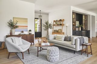 gray couch and armchair in white living room with ikat rug and stool