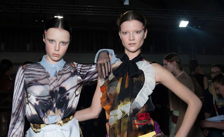 2 female models in decorative patterned blouses pose for the camera