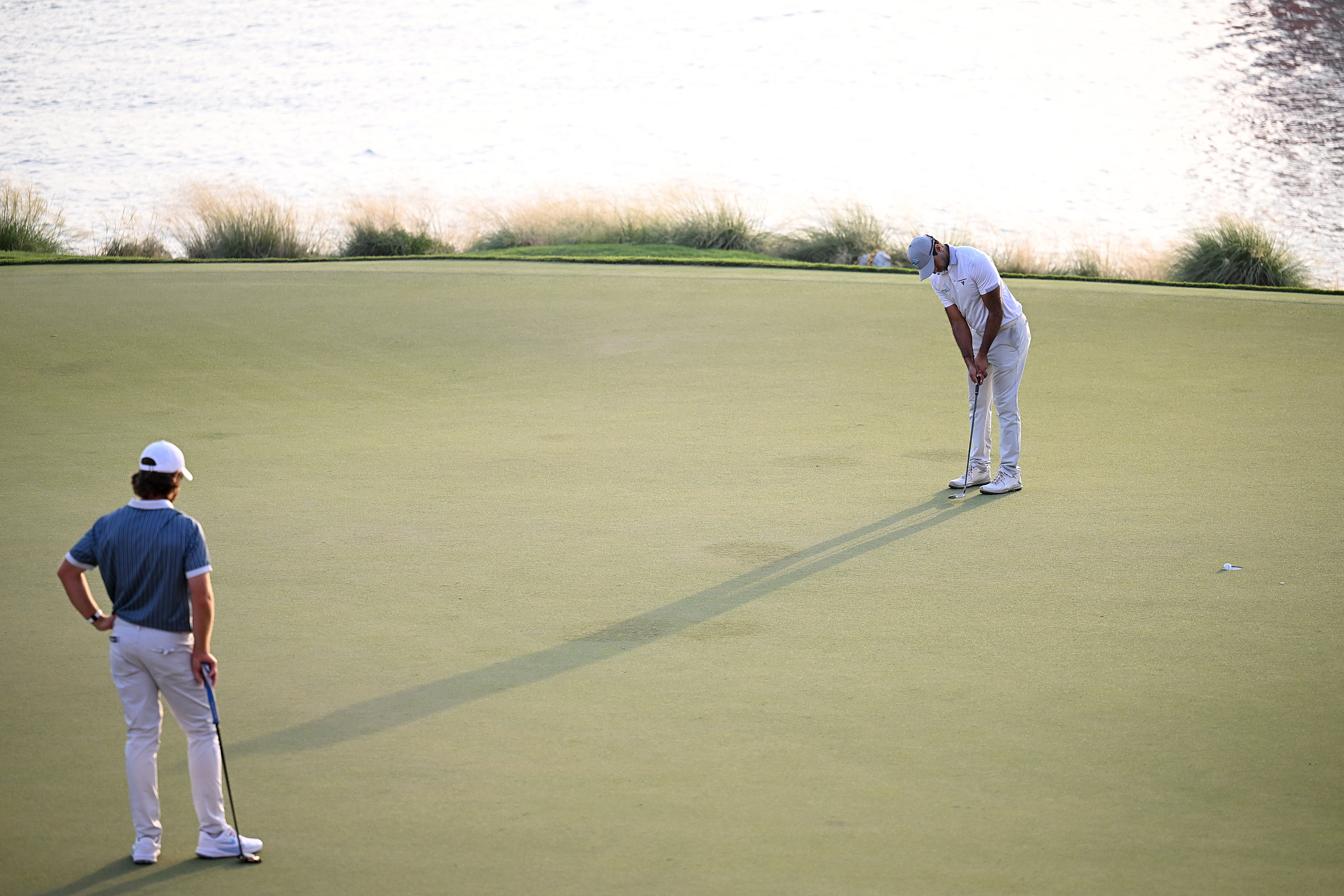 Aaron Rai putts to win the 2025 Abu Dhabi HSBC Championship while Tommy Fleetwood looks on in the foreground