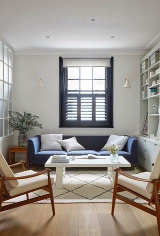 Small white living room with blue sofa and Berber rug