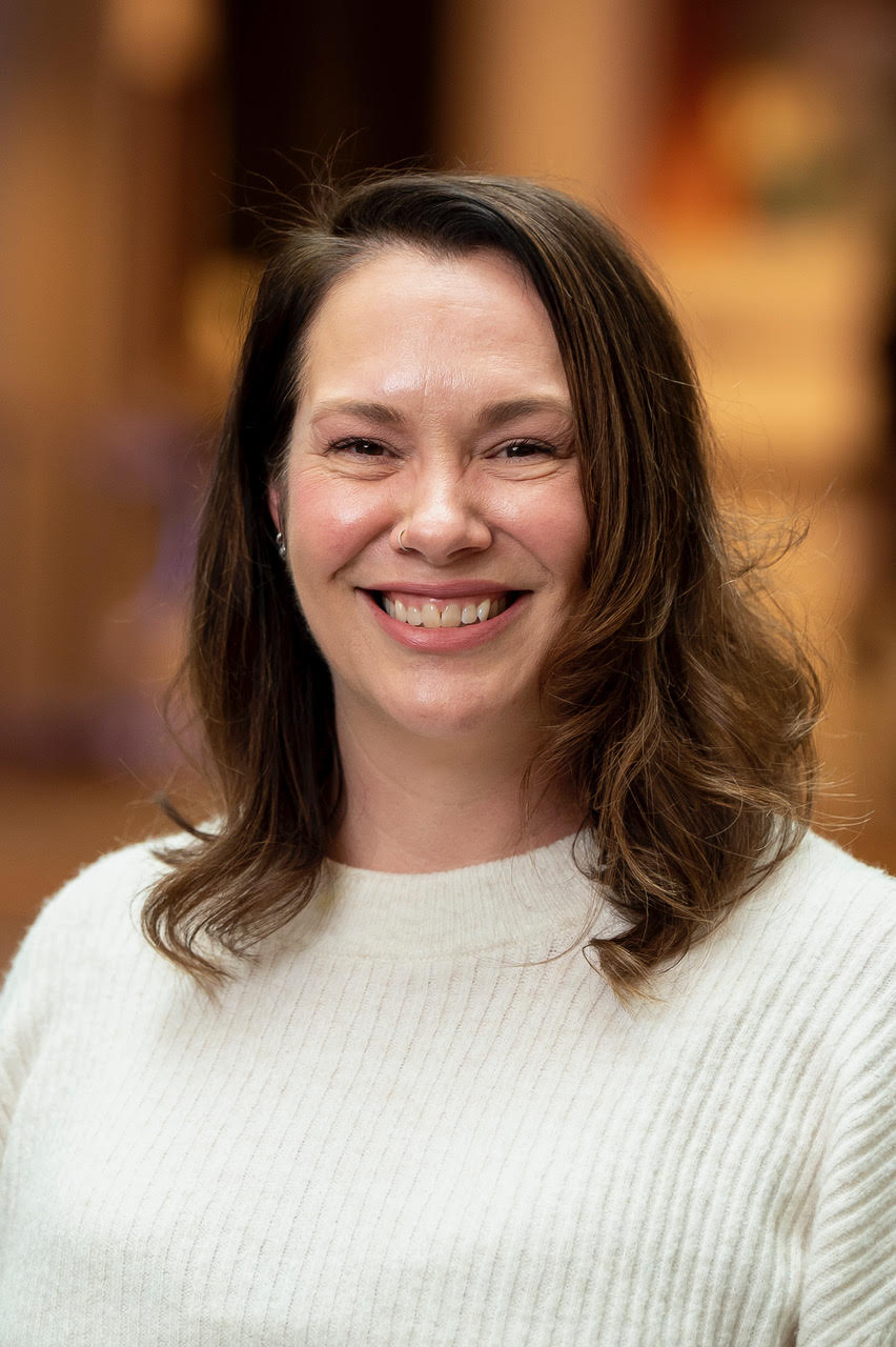 headshot of woman with brown shoulder length hair and cream knitted sweater