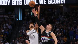 Victor Wembanyama of the San Antonio Spurs and Nikola Jokic of the Denver Nuggets battle for the opening tip-off during an NBA game