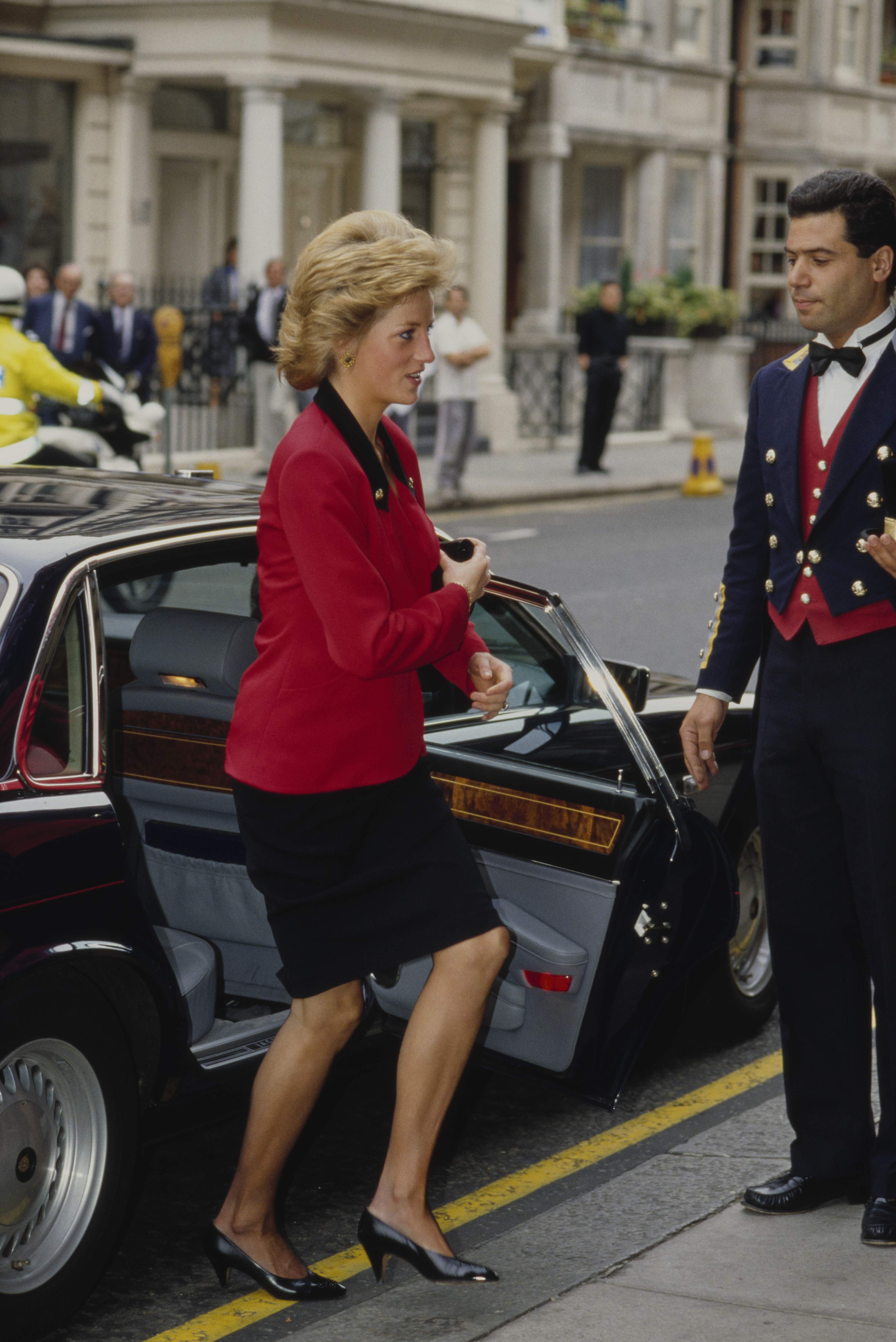 Princess Diana getting out of a car in a red blazer and black skirt