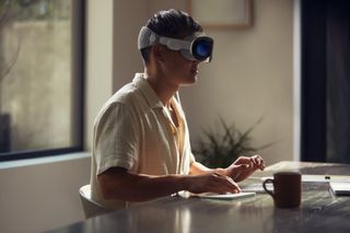A man sat at a desk wearing an Apple Vision Pro headset