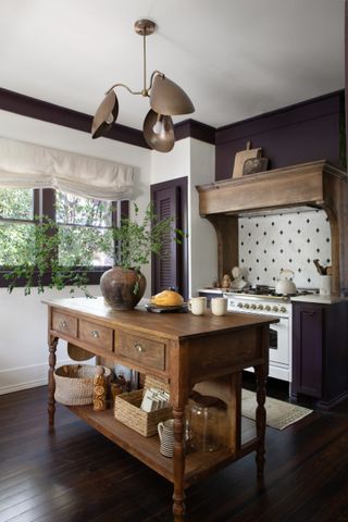 A country kitchen with dark plum trim and cabinetry, a white range oven, and a wooden kitchen island