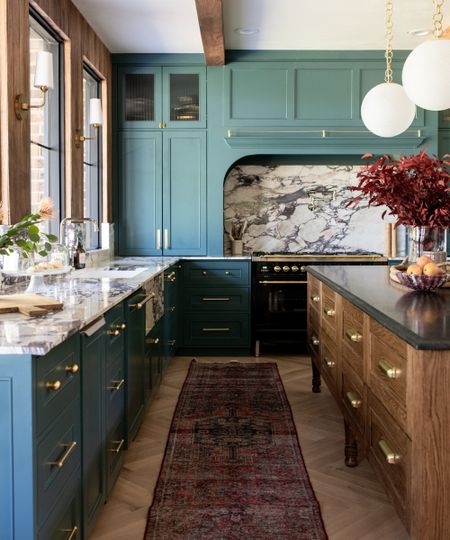 A kitchen with smoky blue-green cabinets, a wooden island, and brass accents