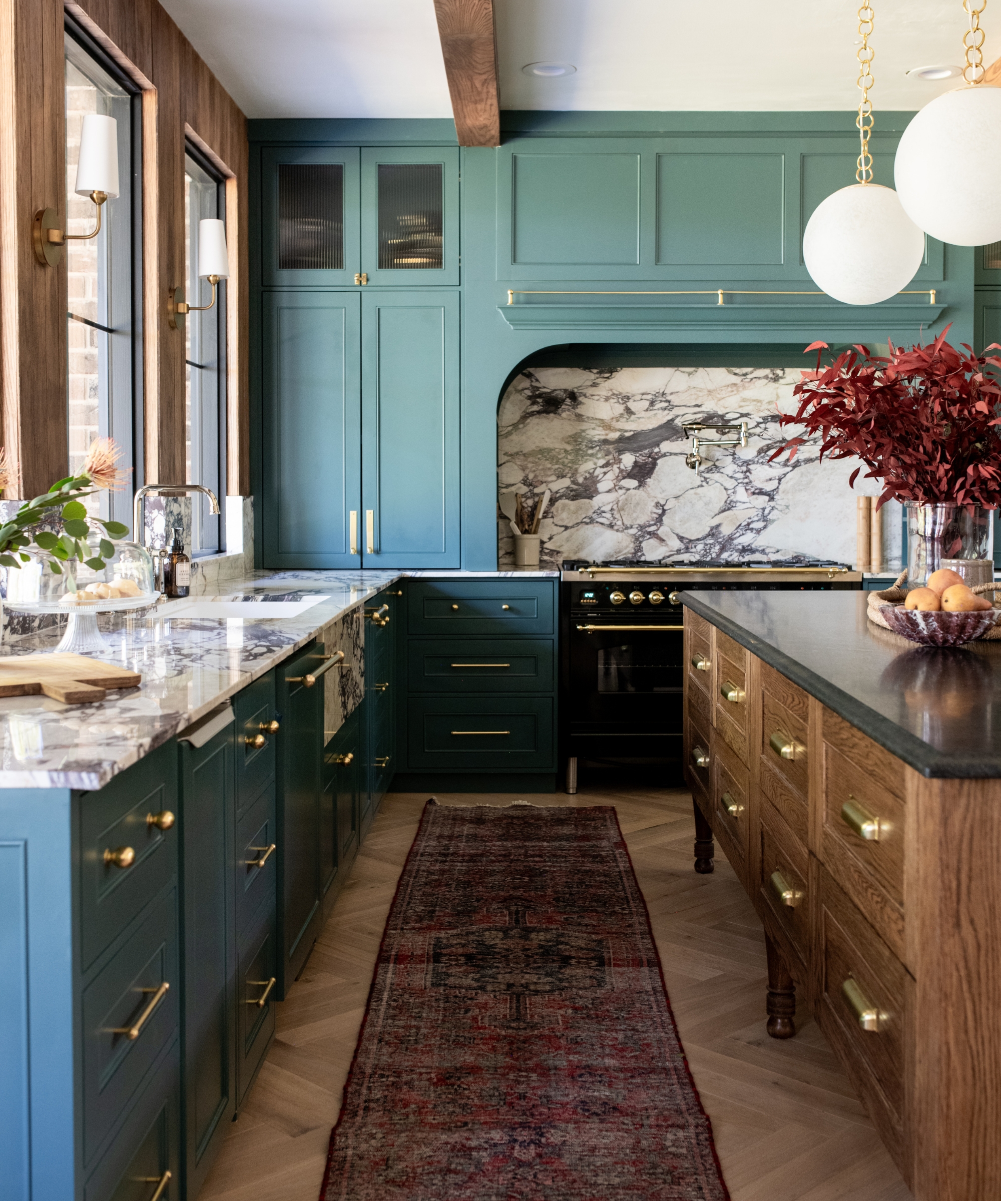 A kitchen with smoky blue-green cabinets, a wooden island, and brass accents