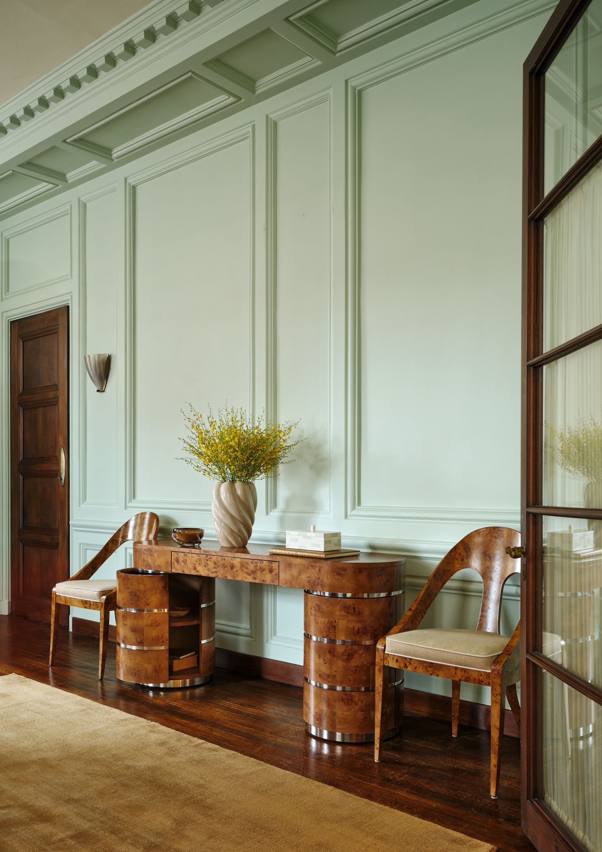 a burl wood credenza with a vase of flowers on it and two chairs on either side