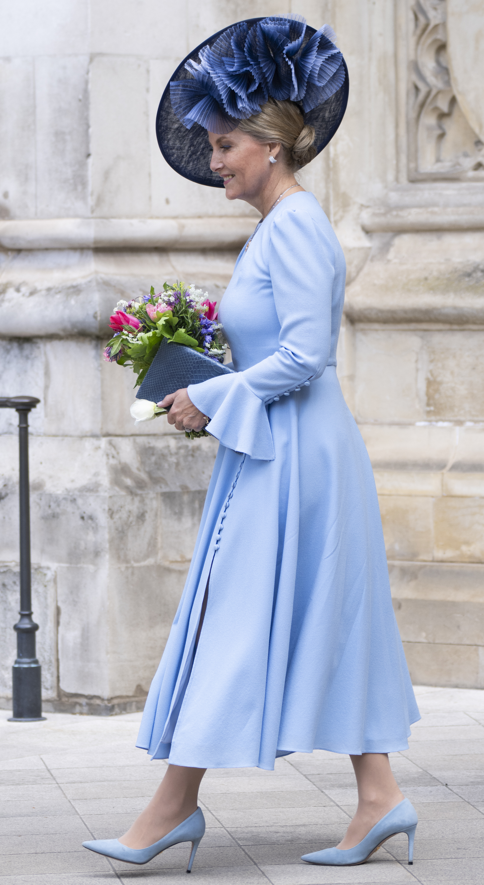 Duchess Sophie wearing a blue dress and hat holding flowers