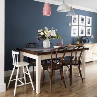 blue dining room with white highchair and pink pendant lamp