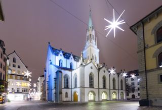 Brightly lit stars hang over a church and buildings in St. Gallen, Switzerland