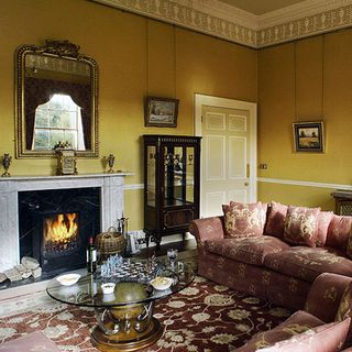Clarenden House living room with mustard walls, sofas and log fire