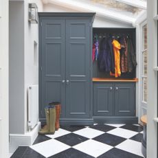 Boot room with black and white tiled floor and bluefitted cupboards