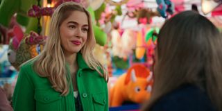 Lizzie wearing a green jacket at a carnival.