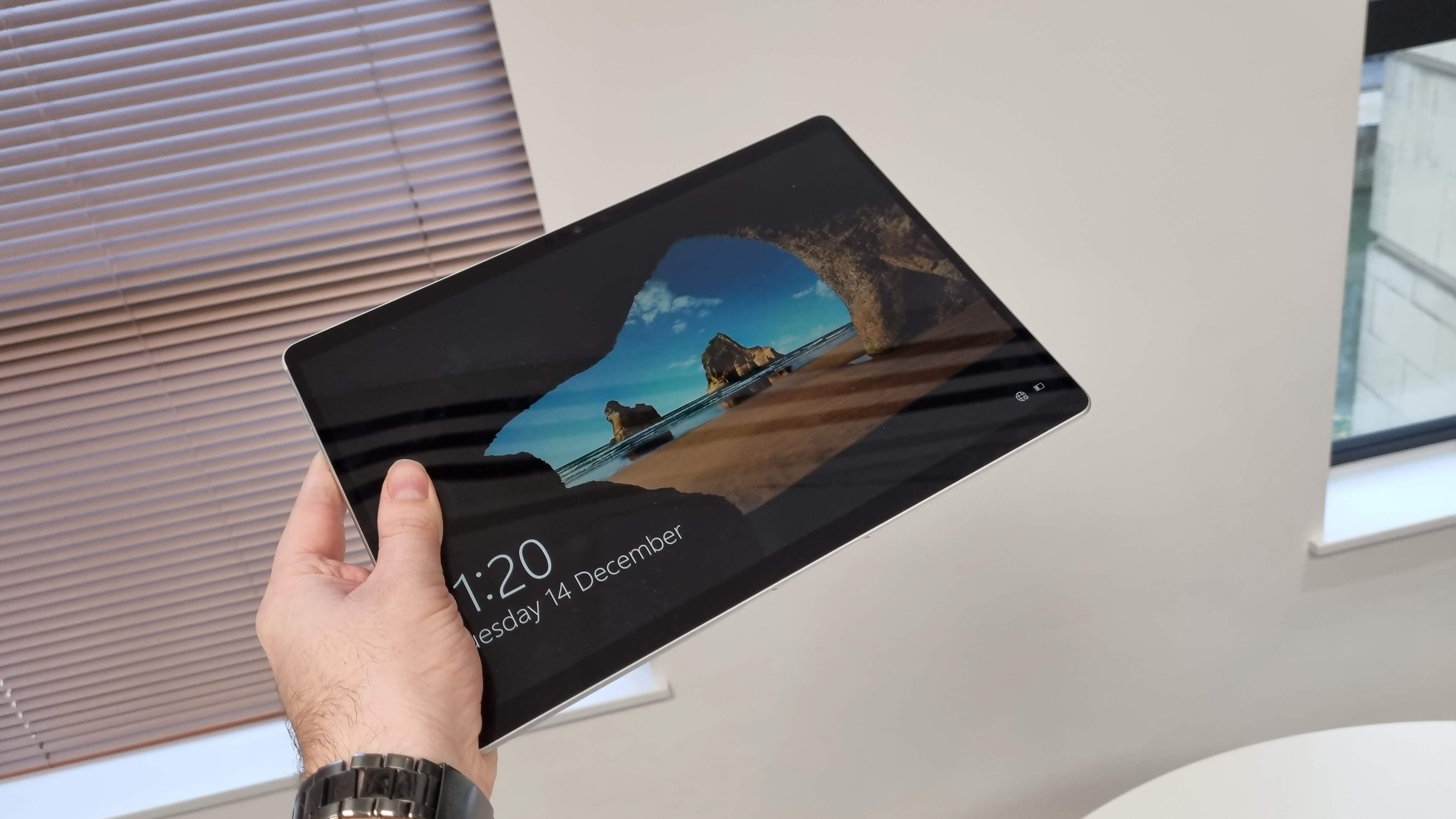 A hand holding a Microsoft Surface Pro 8 tablet