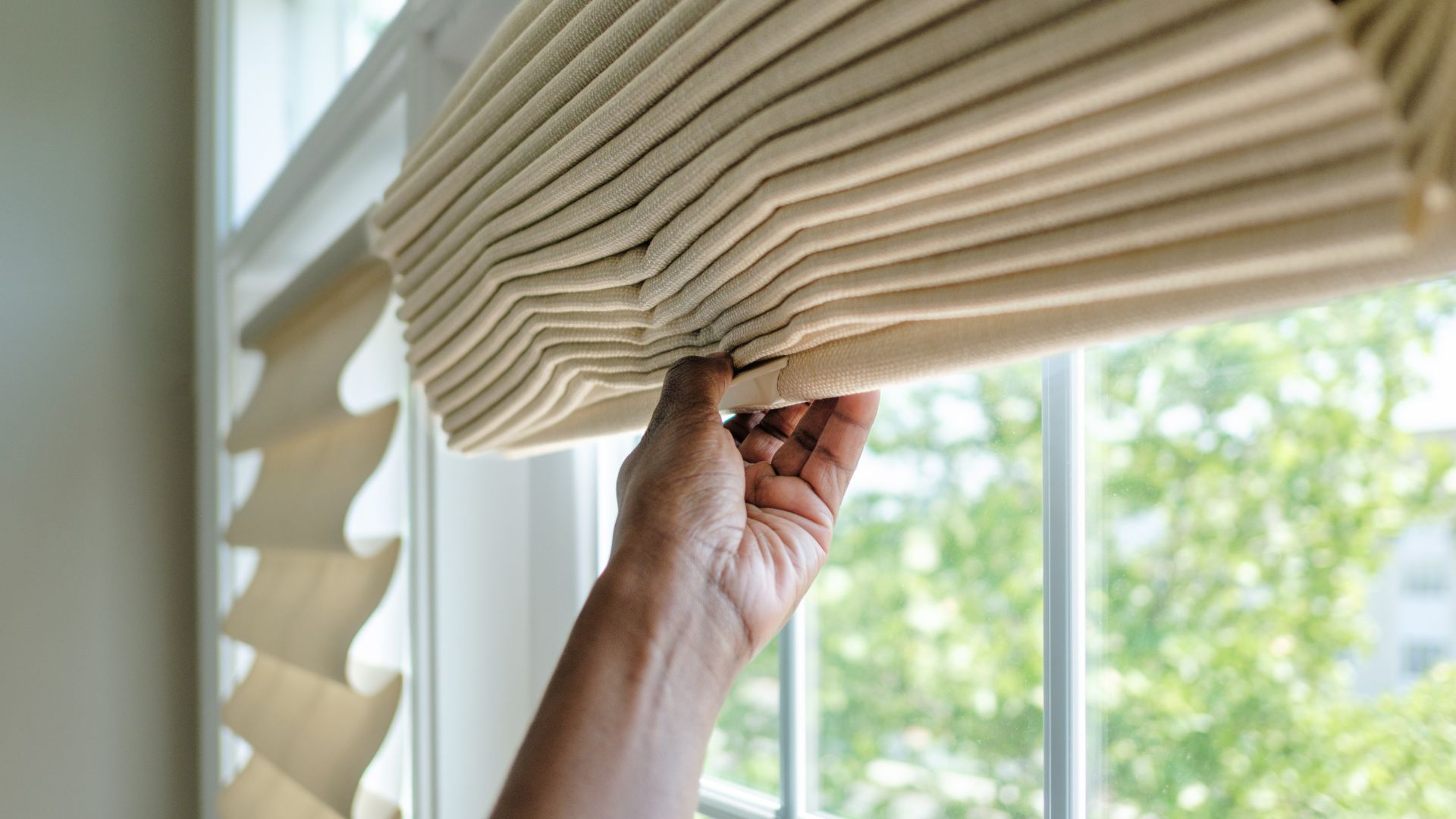 picture of woman putting up blinds in home