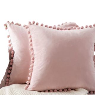 Two pink square throw pillows with pom pom trims